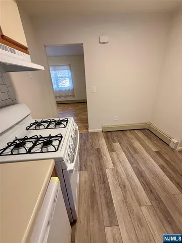 a kitchen with a stove and wooden floor