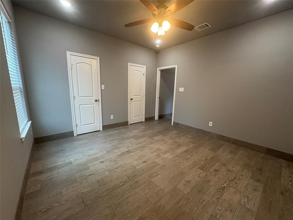 216 Cleveland Street, Unit B Cleburne, TX 76031 - Photo 20 of 26 an empty room with chandelier fan and windows