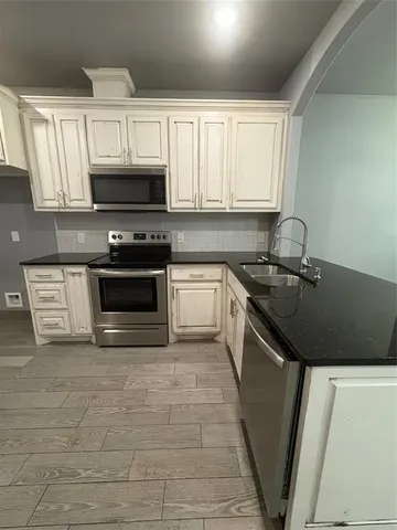 a kitchen with granite countertop a sink a stove top oven and cabinetry
