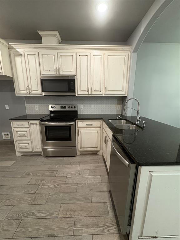 216 Cleveland Street, Unit B Cleburne, TX 76031 - Photo 5 of 26 a kitchen with granite countertop a sink a stove top oven and cabinetry