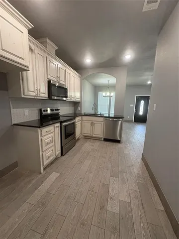 a large kitchen with stainless steel appliances granite countertop a stove a sink dishwasher and a microwave oven on the blue kitchen countertops with wooden floor