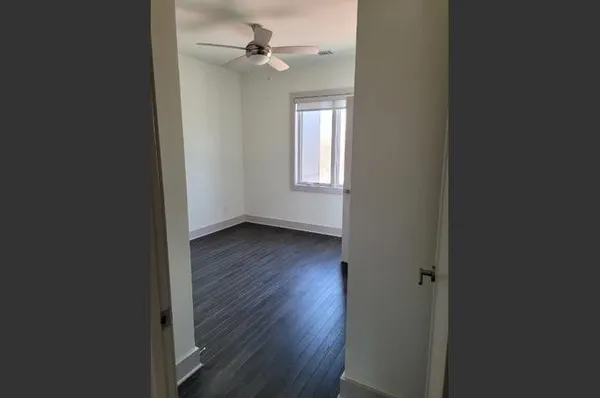 an empty room with wooden floor fan and windows