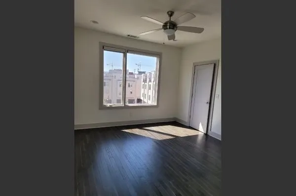 a view of an empty room with wooden floor and a window