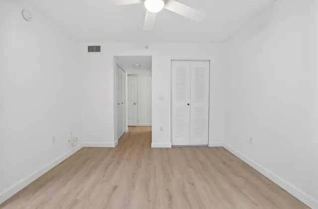 an empty room with wooden floor and a ceiling fan