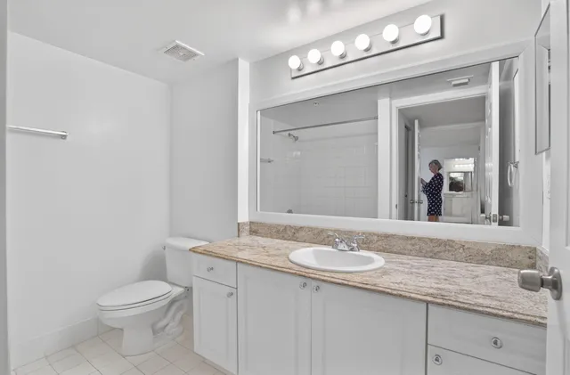 a bathroom with a granite countertop sink a toilet and a mirror
