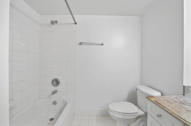 a bathroom with a granite countertop bathtub toilet and a shower