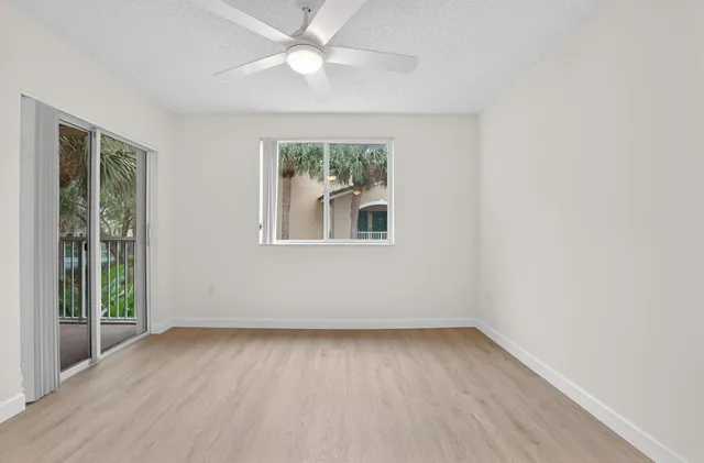 an empty room with a window and a ceiling fan