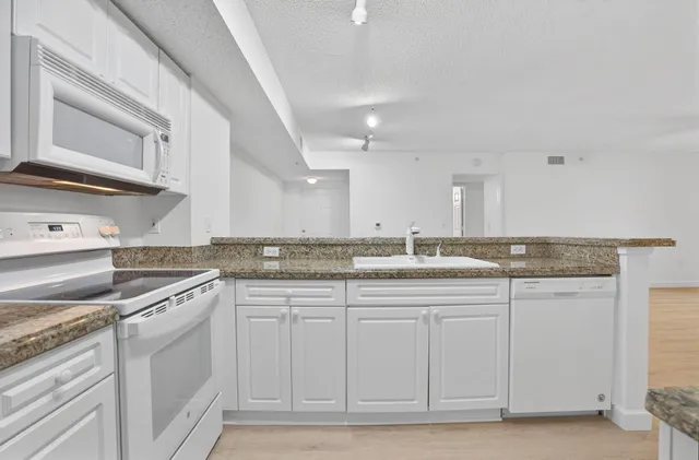 a kitchen with granite countertop white cabinets and white appliances