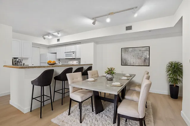 a open dining room with stainless steel appliances kitchen island granite countertop a dining table and chairs with wooden floor