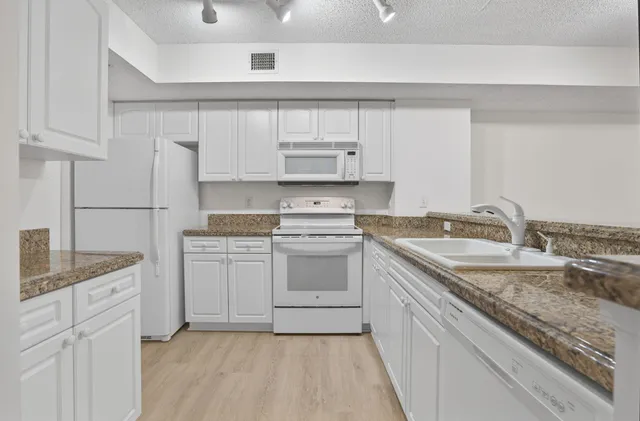 a kitchen with granite countertop a sink stove and cabinets