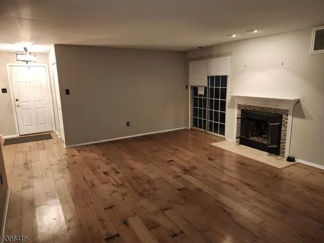 an empty room with wooden floor fireplace and windows