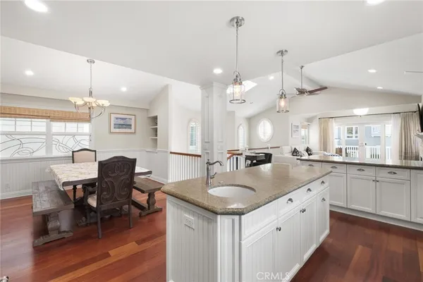 a kitchen with stainless steel appliances granite countertop a sink a refrigerator and a wooden floor