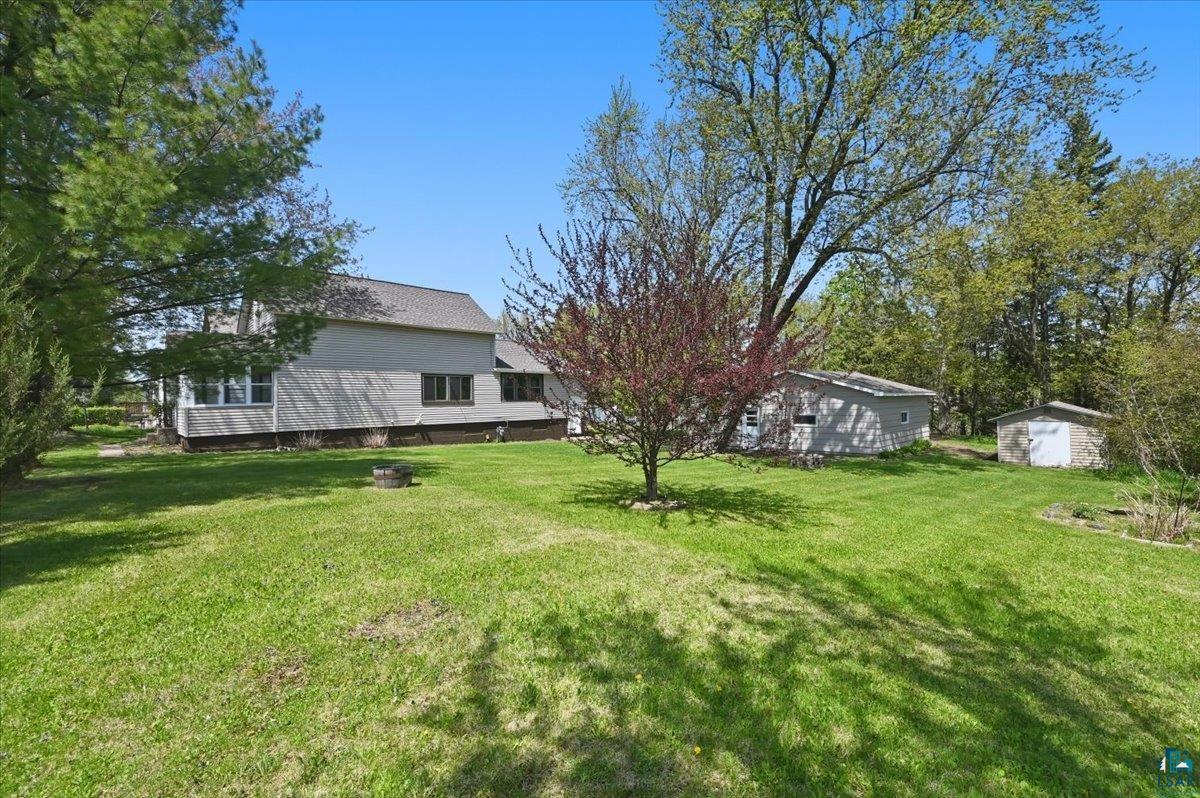 5319 East 3rd Street Superior, WI 54880 - Photo 6 of 33 Expansive green lawn featuring mature trees, a detached storage building, and an additional shed