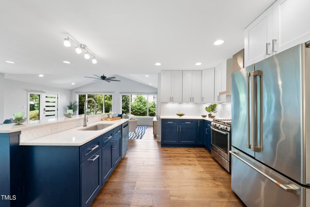 a large kitchen with stainless steel appliances kitchen island granite countertop a refrigerator and a sink