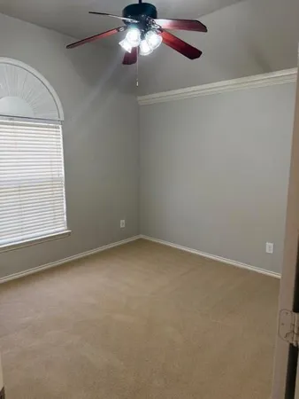 an empty room with a chandelier fan and windows