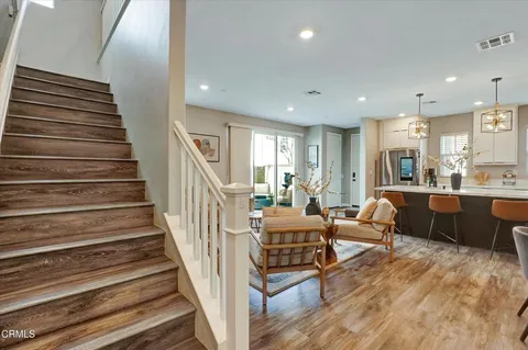 a living room with couches and kitchen view with wooden floor