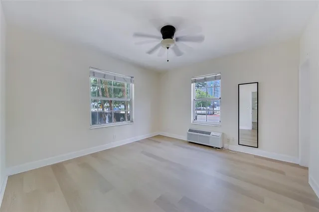 an empty room with windows and ceiling fan