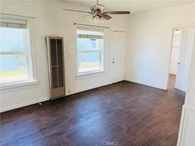 an empty room with wooden floor chandelier and windows