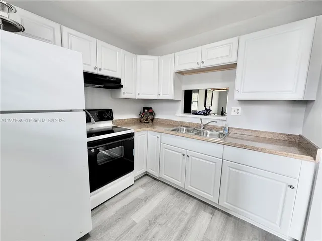 a kitchen with granite countertop white cabinets and white appliances
