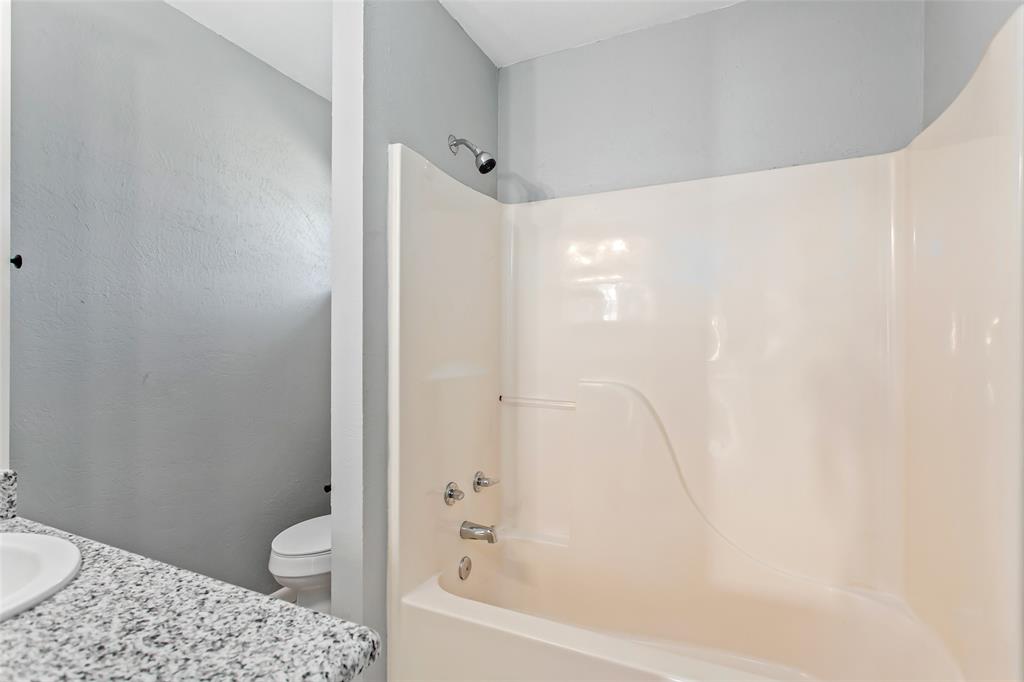 712 Billups Street Van Alstyne, TX 75495 - Photo 29 of 38 a bathroom with a granite countertop bathtub shower sink and toilet