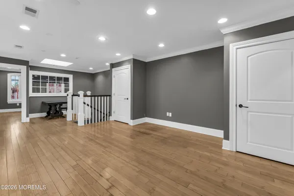 a view of an empty room with wooden floor and windows