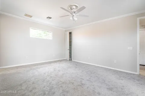 an empty room with a chandelier fan and windows