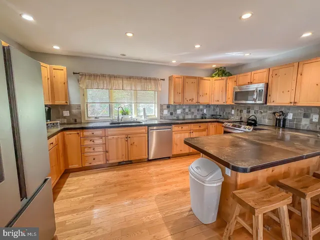 a kitchen with stainless steel appliances granite countertop a sink a counter top space and a large window