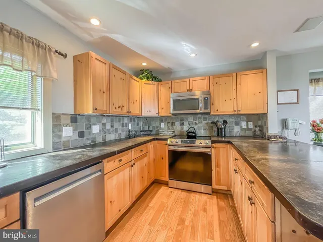 a kitchen with stainless steel appliances granite countertop wooden cabinets a stove a sink and a window