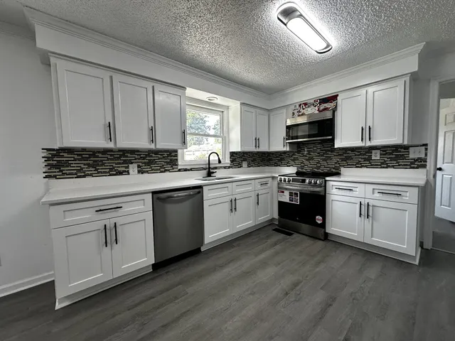 a kitchen with white cabinets sink and appliances