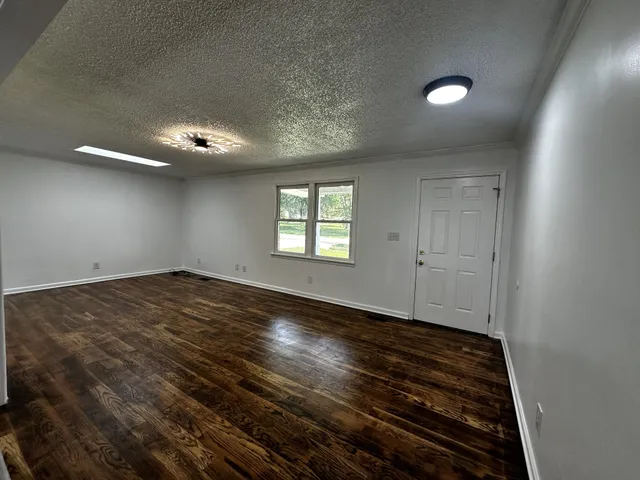 an empty room with wooden floor cabinet and windows