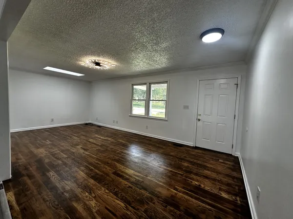 an empty room with wooden floor cabinet and windows