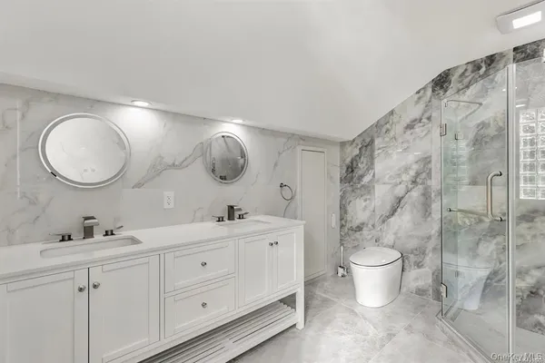 a spacious bathroom with a double vanity sink a toilet and a mirror