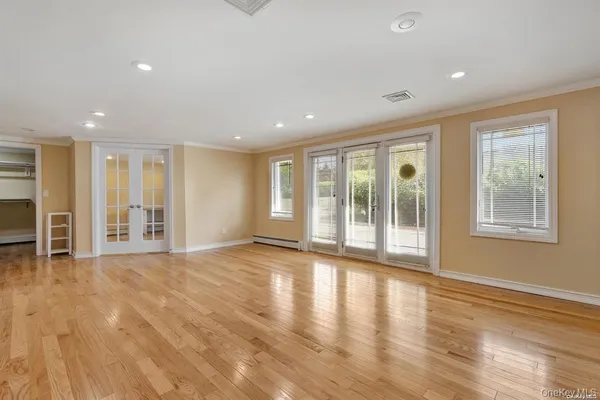 a view of an empty room with a window and wooden floor