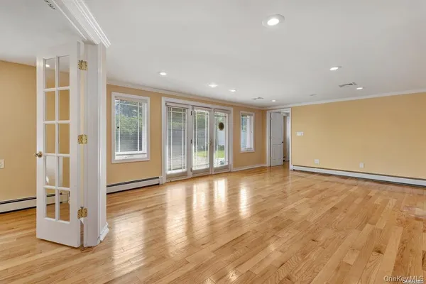 a view of an empty room with wooden floor and windows
