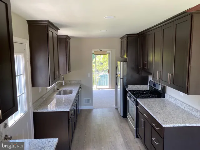 a kitchen with kitchen island granite countertop a sink stove and refrigerator