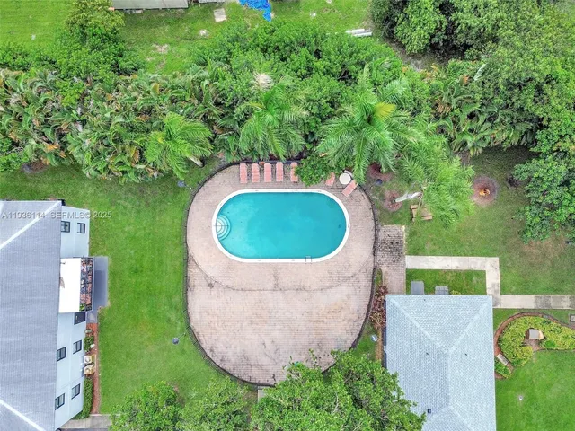 an aerial view of a house with outdoor space and trees all around