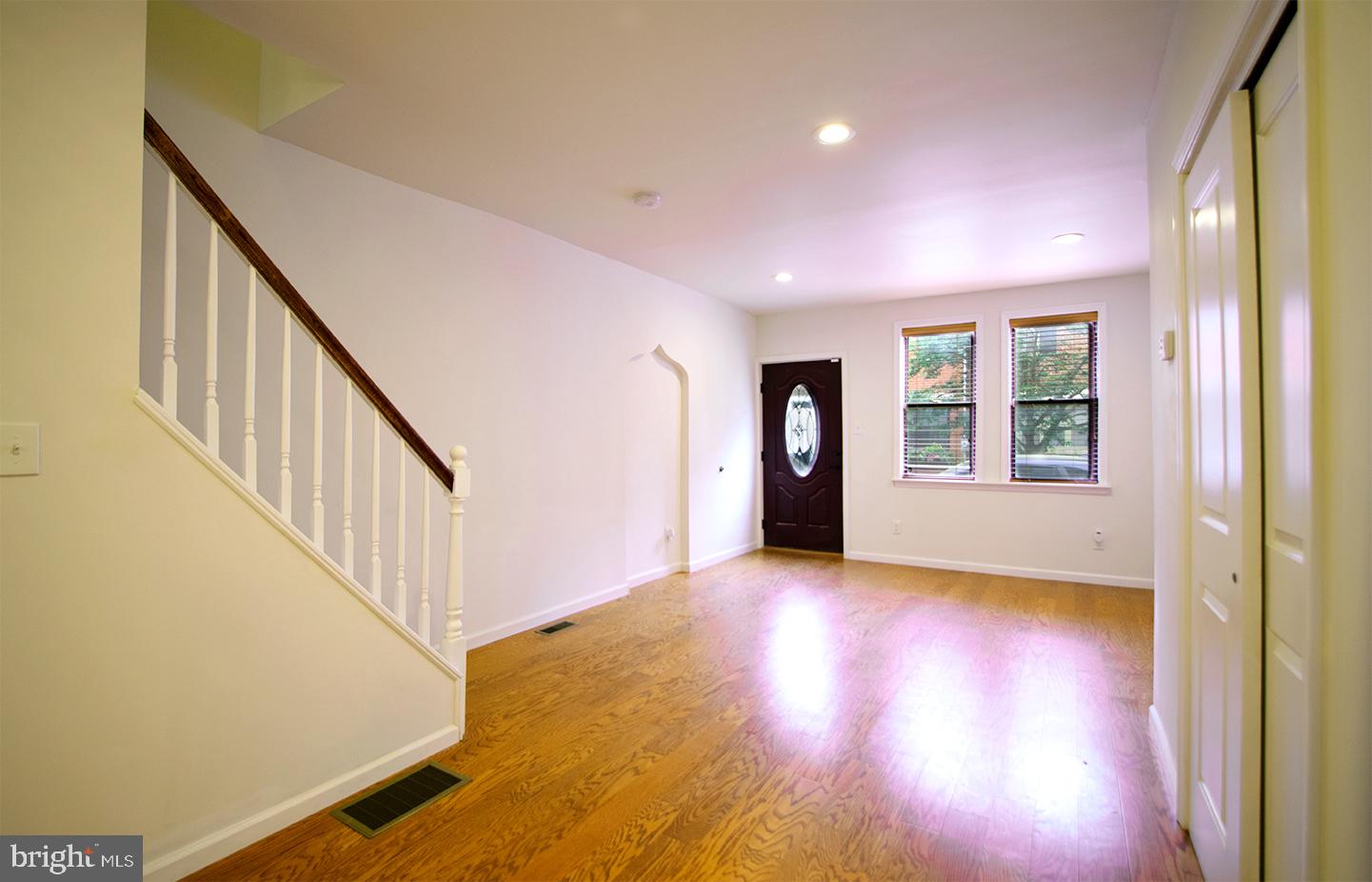 a view of an empty room with wooden floor and stairs