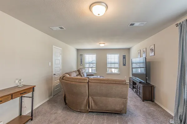 a living room with furniture a flat screen tv and a refrigerator
