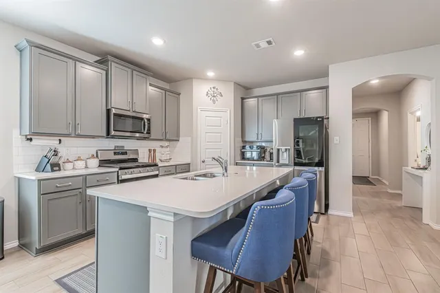 a kitchen with stainless steel appliances granite countertop a sink a stove a refrigerator cabinets and chairs