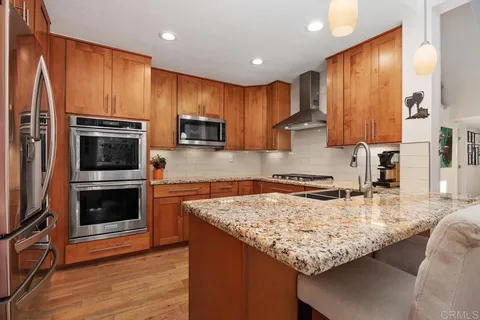 a kitchen with kitchen island granite countertop wooden cabinets a sink and a stove