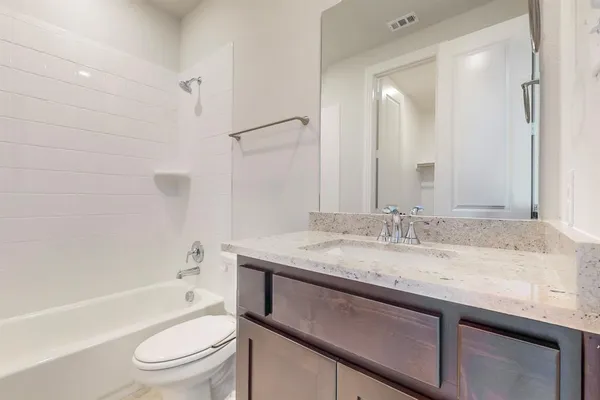 a bathroom with a granite countertop sink toilet mirror and bathtub