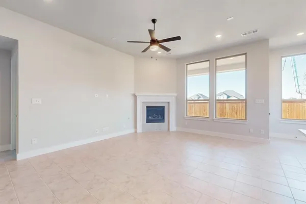 an empty room with windows and fireplace