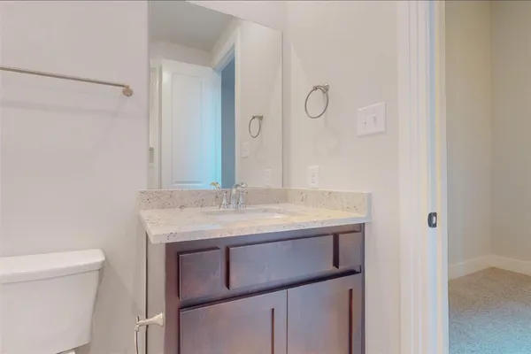 a bathroom with a granite countertop sink and a toilet