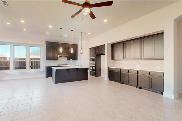 a large kitchen with a large counter top a sink stainless steel appliances and cabinets