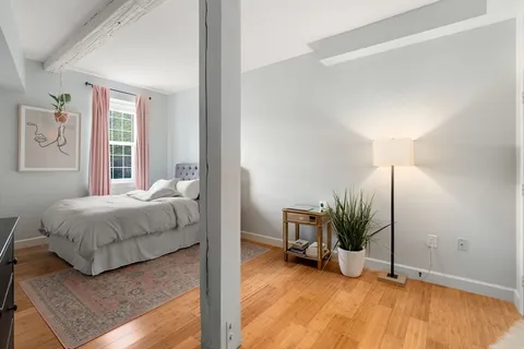 a bedroom with a bed and a potted plant on the dresser