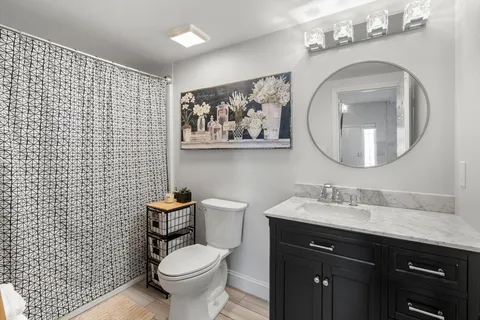 a bathroom with a toilet sink vanity and mirror
