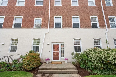 a front view of a building with garden and entryway