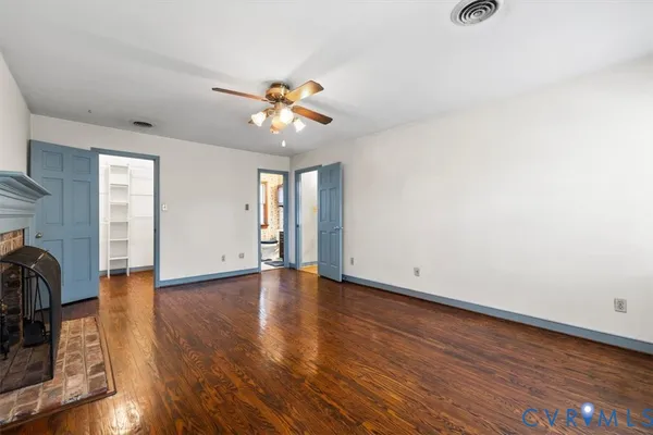an empty room with wooden floor and ceiling fan