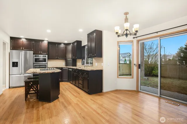 a kitchen with kitchen island granite countertop stainless steel appliances cabinets a sink and a counter top space