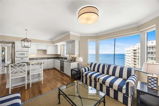 a living room with furniture kitchen view and a large window